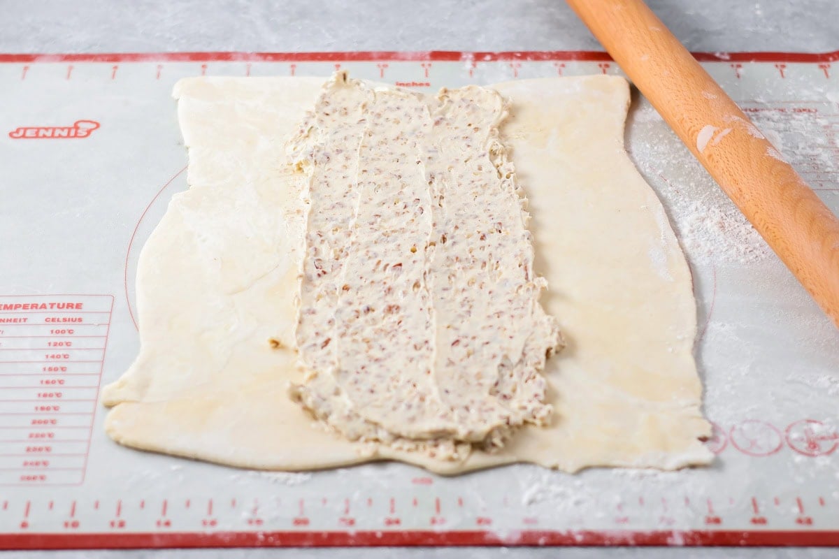 Dough rolled into a rectangle with pecan filling spread down the center.