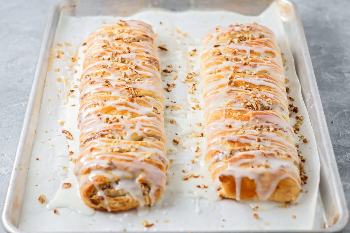 A pair of baked Danish kringles covered with glaze and chopped pecans. 