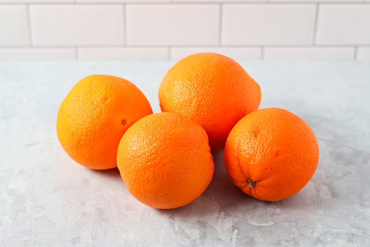 Four navel oranges on a kitchen counter.
