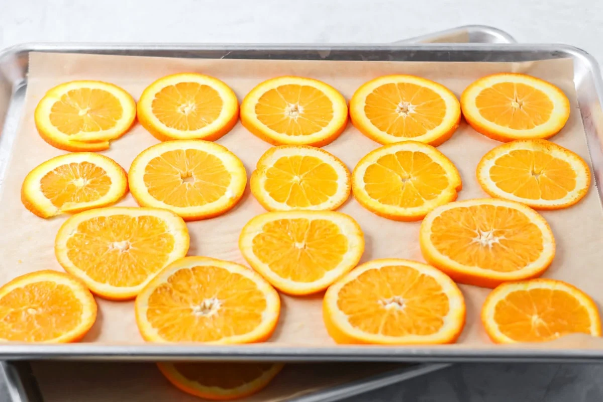Several orange slices on a parchment paper lined baking sheet.