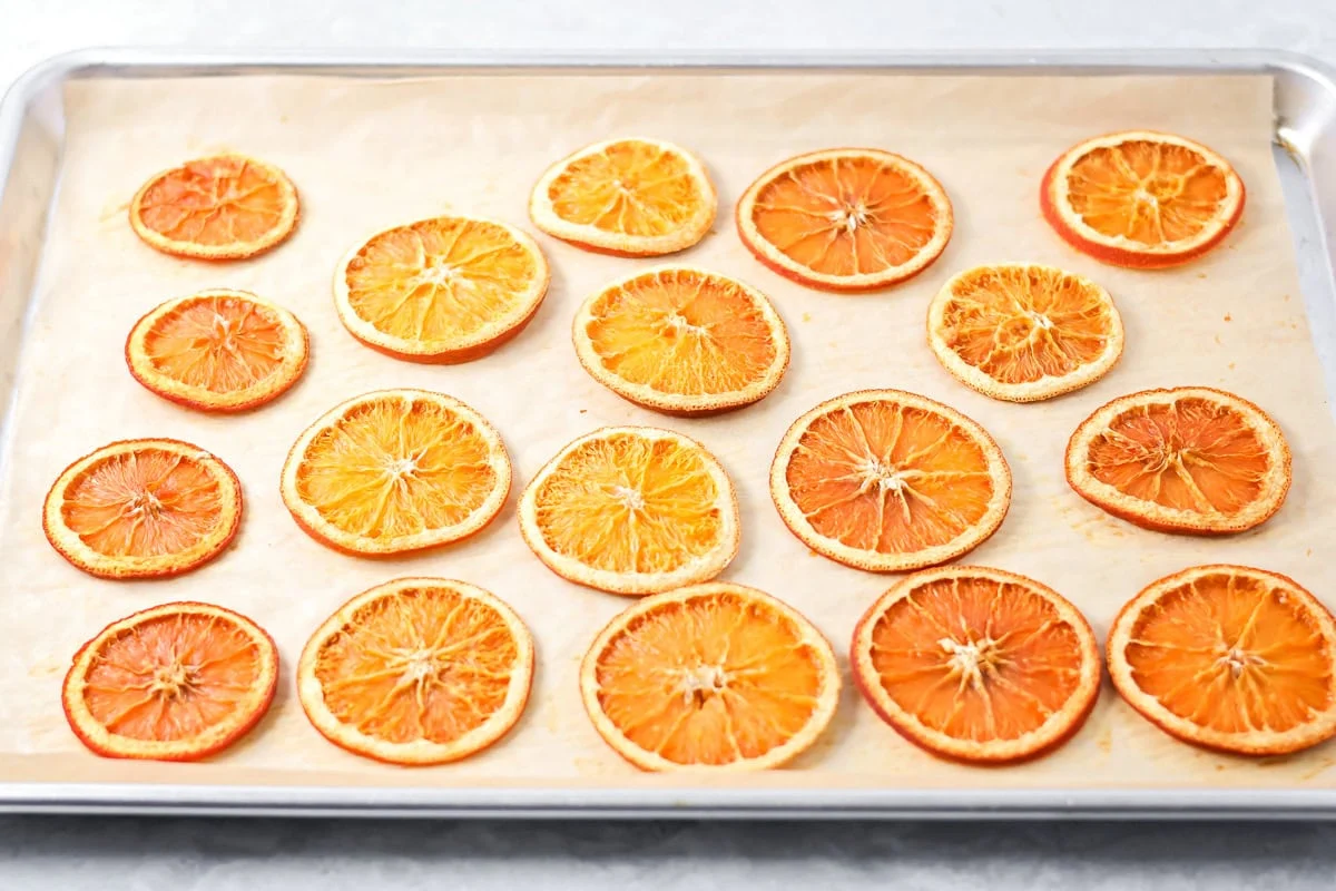 Several baked orange slices cooling on a baking sheet.