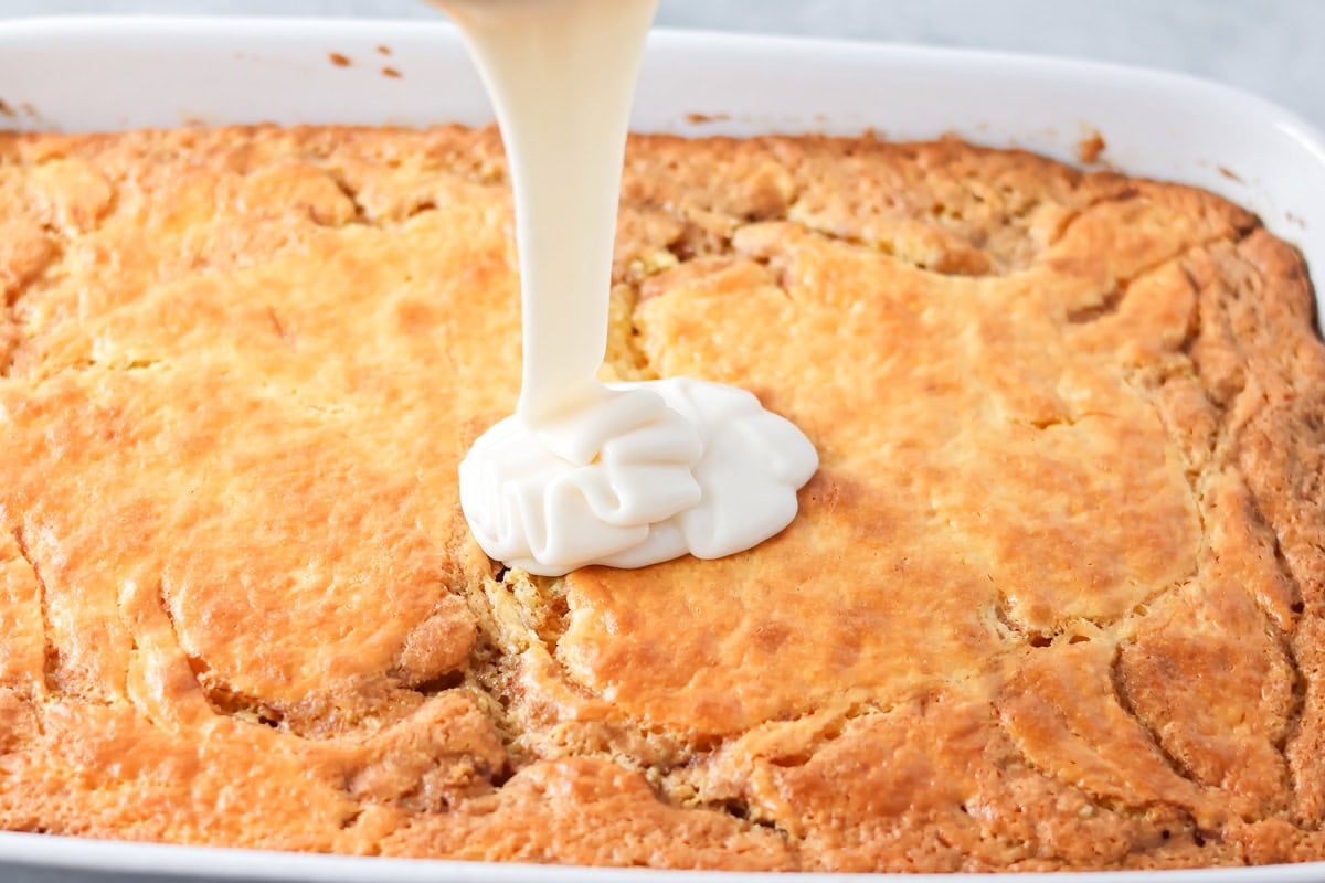 Glaze being poured over honey bun cake recipe.