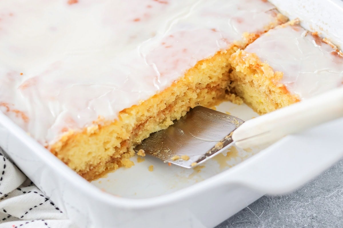 A honey bun cake in a baking dish with 2-3 slices missing.