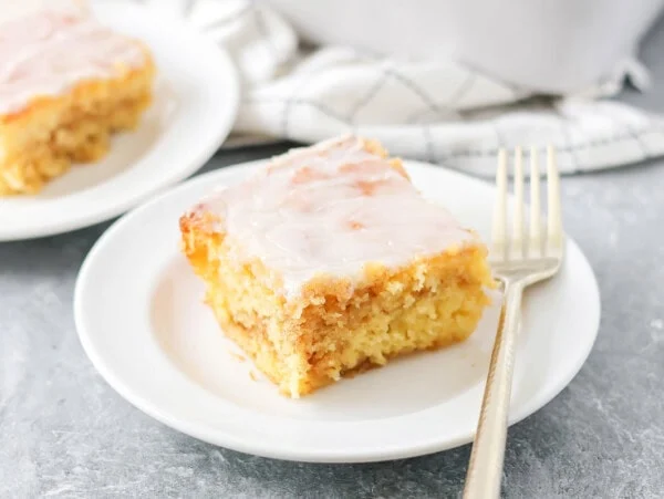 Slice of honey bun cake recipe on white plate.
