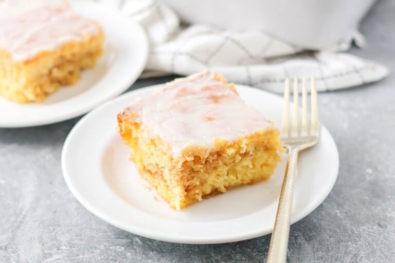 Slice of honey bun cake recipe on white plate.