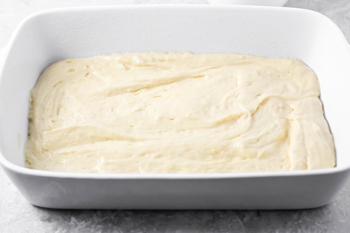 A layer of cake batter in a ceramic baking dish.