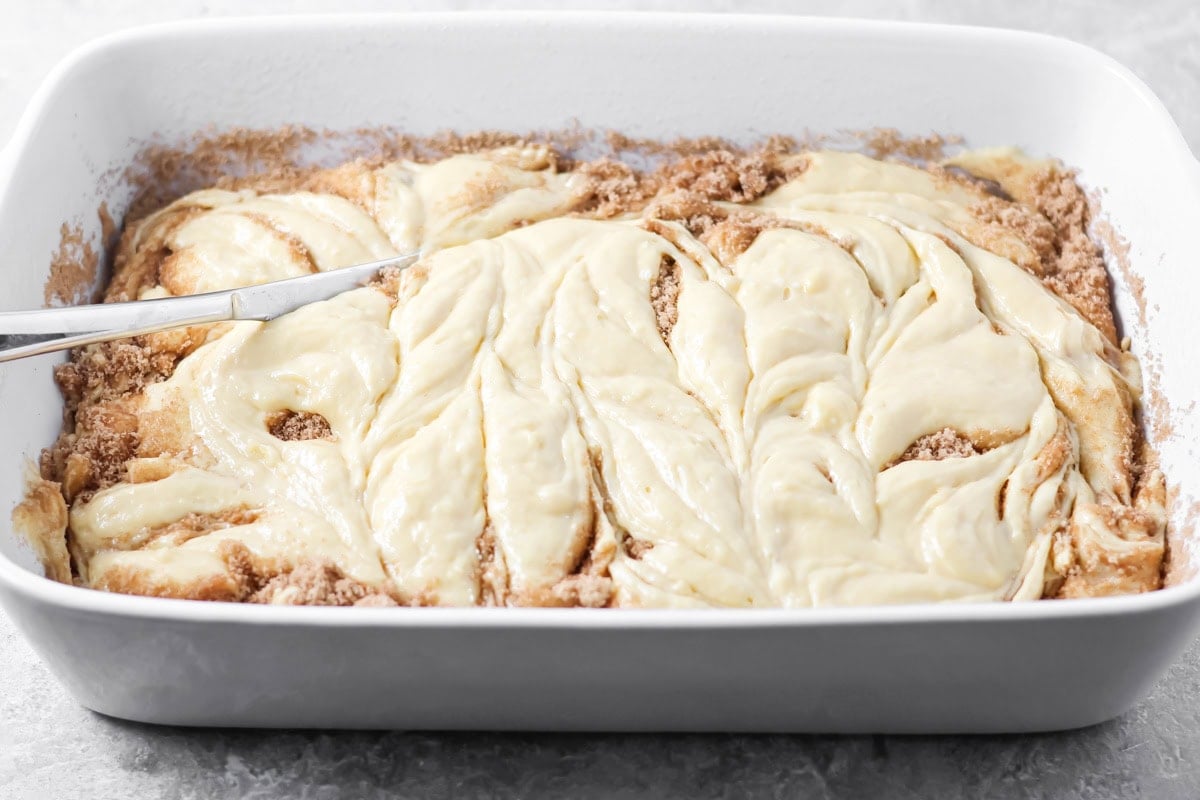 Using a butter knife to swirl the dollops of batter with the cinnamon sugar.