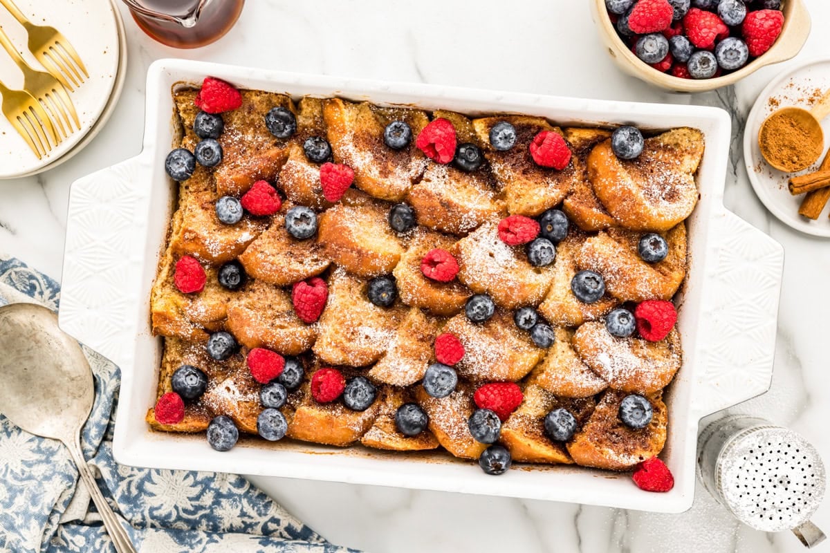Oven baked French toast sprinkled with powdered sugar, fresh blueberries and raspberries.