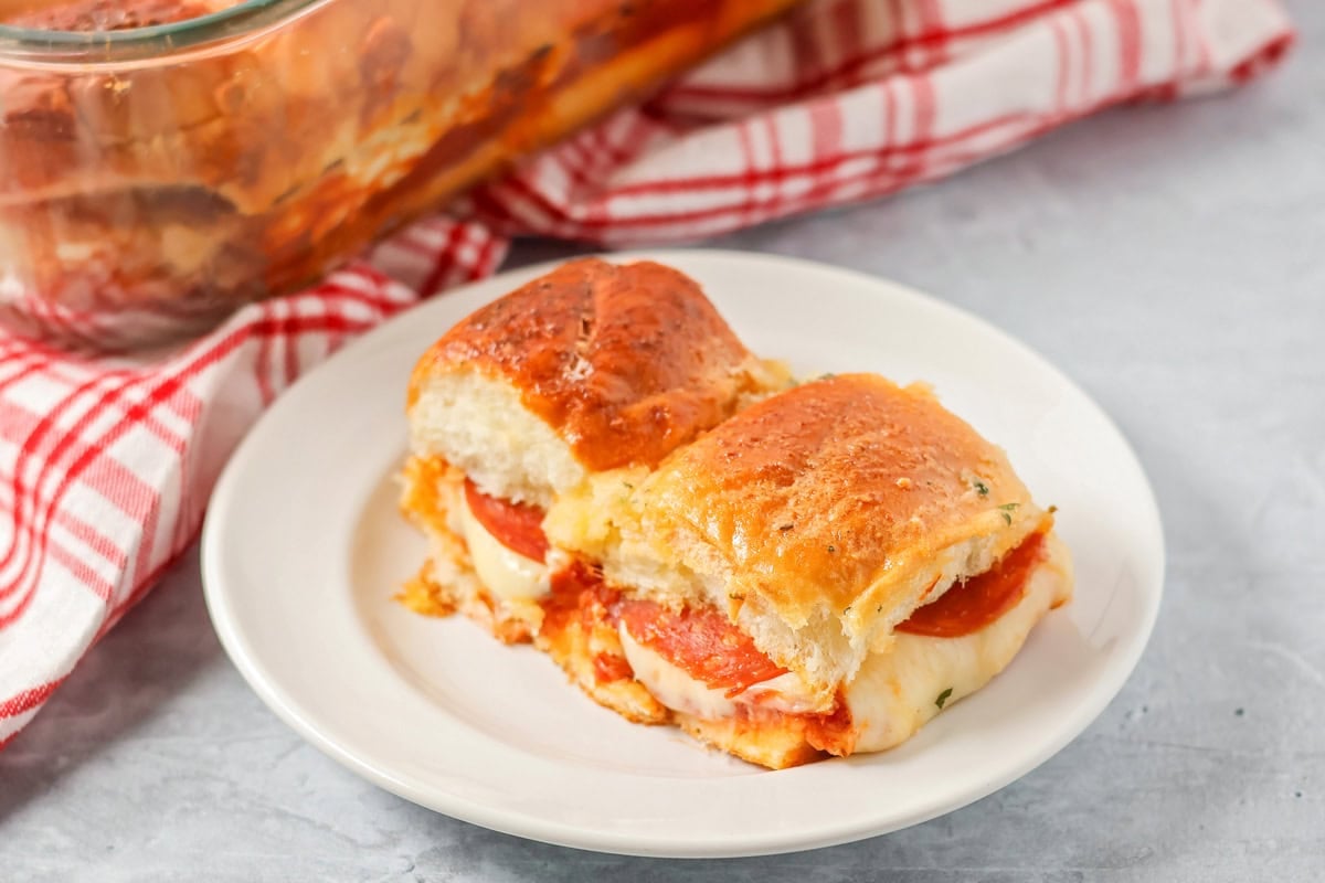 Two baked pizza sliders on a serving plate.