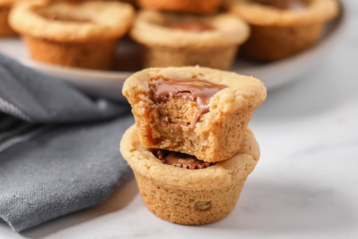A pair of stacked peanut butter cup cookies, the top cookie has a bite taken out of it.