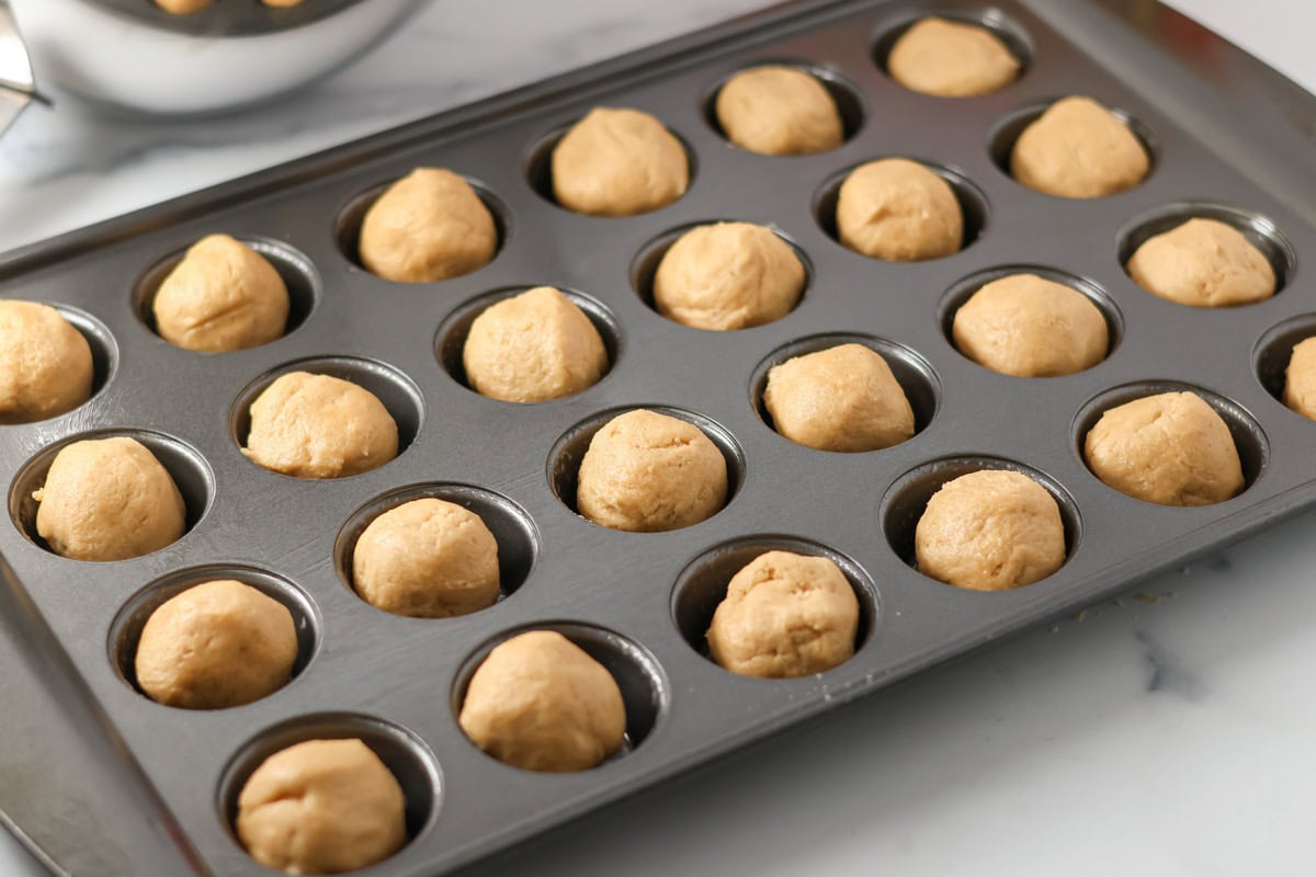 Cookie dough ball in a mini muffin pan.