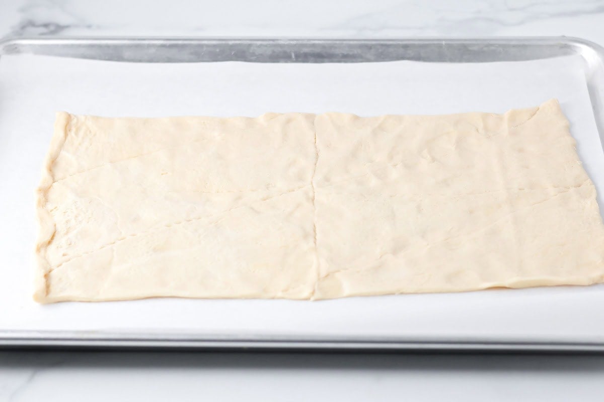 Crescent roll dough rolled out on parchment paper.