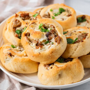 Homemade Sausage pinwheels recipe stacked on top of each other on plate.