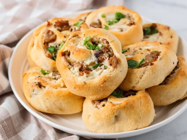 Homemade Sausage pinwheels recipe stacked on top of each other on plate.