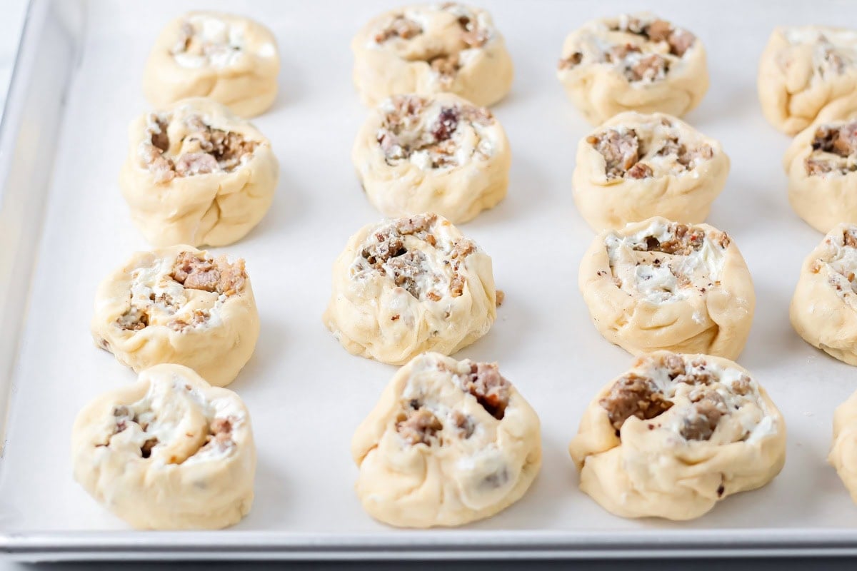 Filled with sausage crumbles and cream cheese, these sausage pinwheels are the ultimate savory snack or party appetizer! Unbaked sausage pinwheels on a baking sheet.
