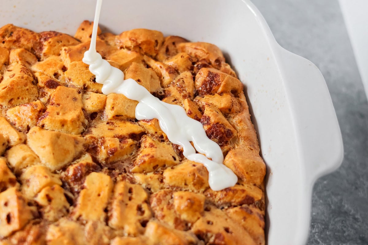 Warm, gooey, and easy to make, this cinnamon roll casserole turns refrigerated rolls into a cozy breakfast everyone will love. Pouring icing over a baked cinnamon roll casserole.