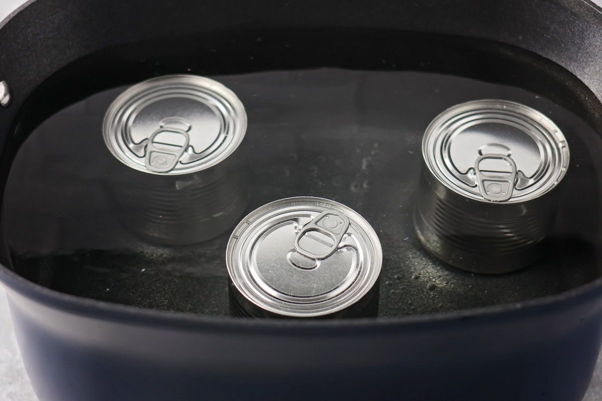 Creamy homemade dulce de leche made easily in the slow cooker with just one ingredient for the perfect caramel flavor. Three cans of sweetened condensed milk in a crock pot covered with water.