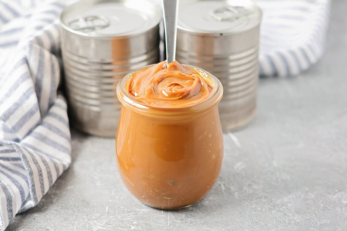 Creamy homemade dulce de leche made easily in the slow cooker with just one ingredient for the perfect caramel flavor. Dolche de leche in a clear glass jar.