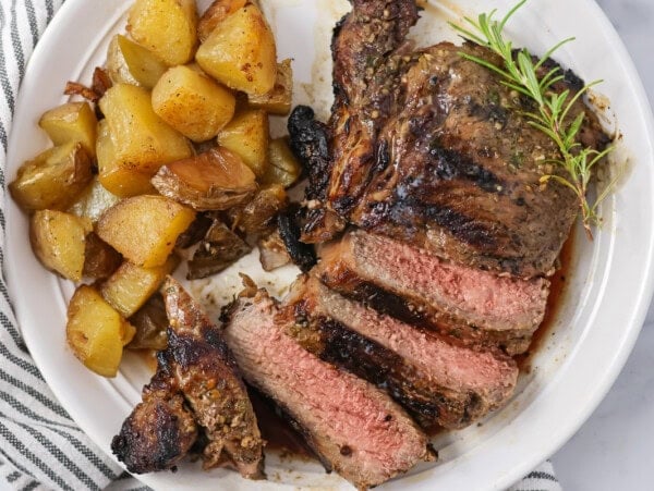 Sliced up Italian rib eye served alongside roasted potatoes.