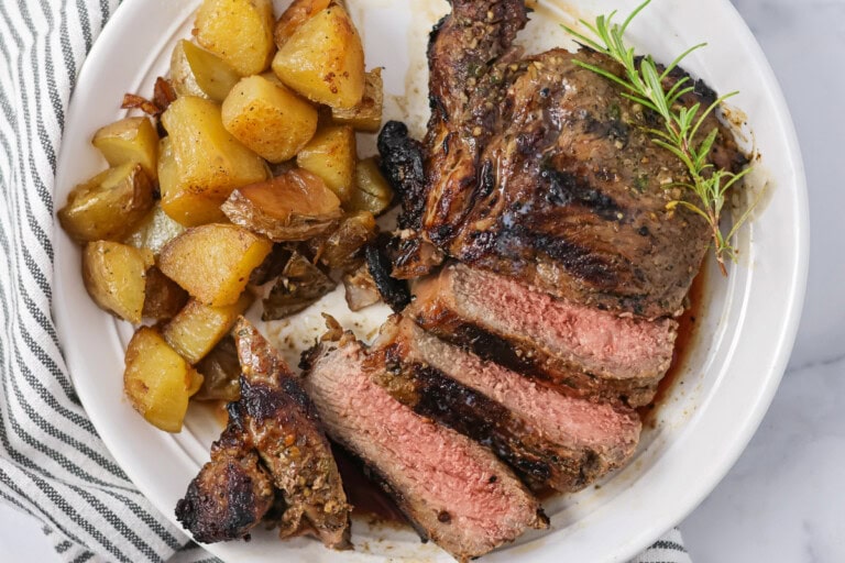 Sliced up Italian rib eye served alongside roasted potatoes.