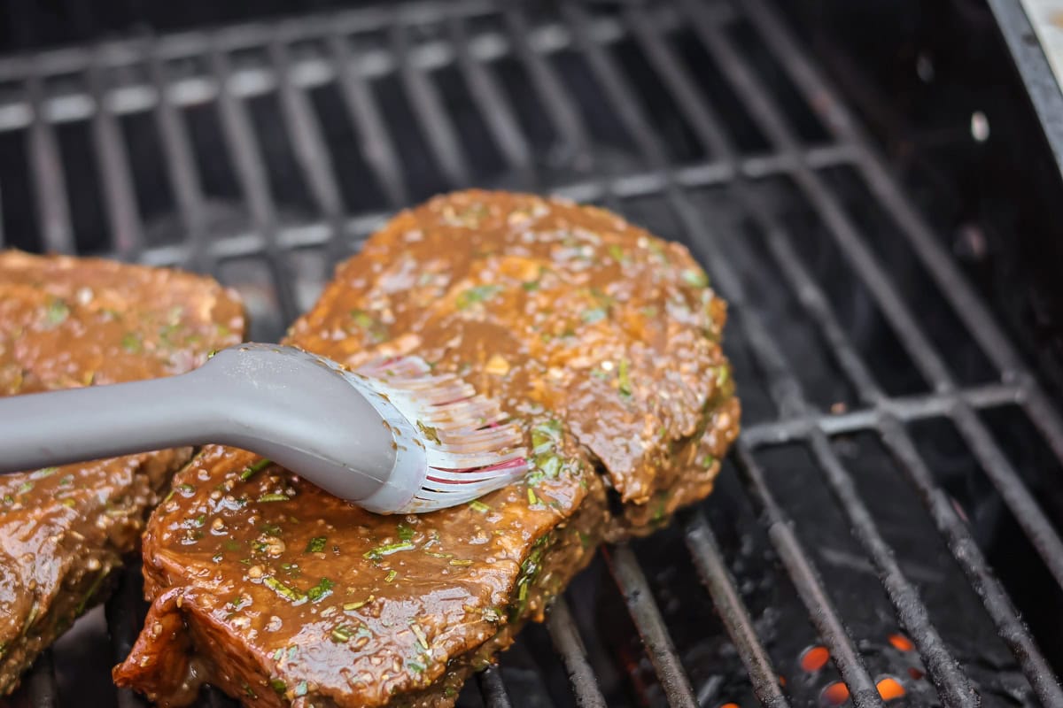 Basting the steaks on the grill.