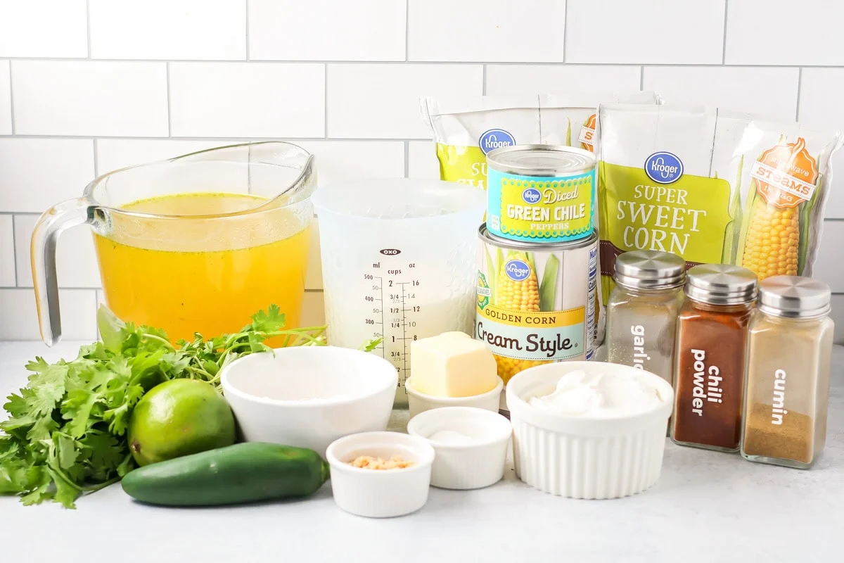 Cozy up with Mexican street corn soup, a creamy one pot dinner with sweet corn, gentle heat, and all your favorite elote toppings. Ingredients for Mexican street corn soup on a white countertop.