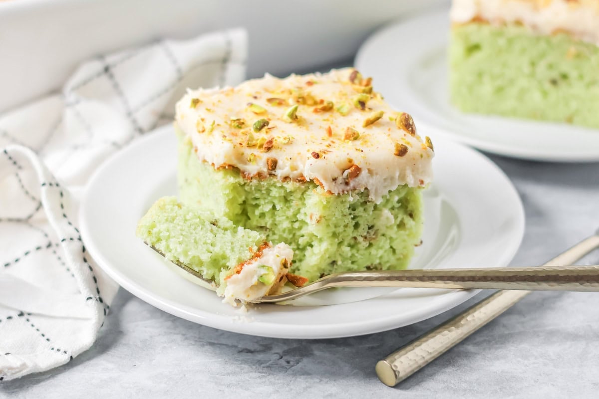 A slice of pistachio cake on a white serving plate.