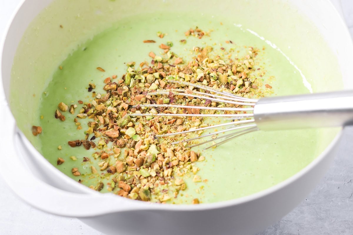 Mixing in chopped pistachios to the green cake batter.