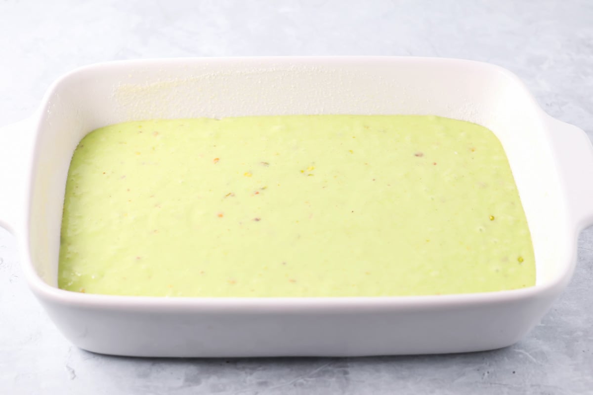 Pistachio cake batter in a white ceramic baking dish.