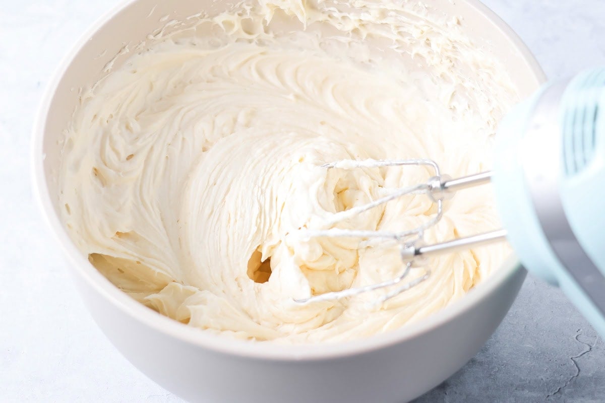 Mixing the cream cheese icing in in a white mixing bowl.