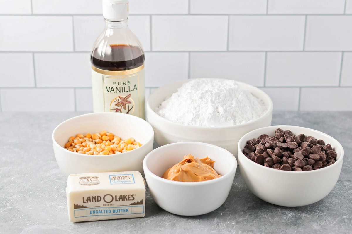 Puppy Chow Popcorn is an irresistible sweet and salty snack that's easy to make and guaranteed to be a hit. Ingredients to make puppy chow popcorn on a kitchen counter.