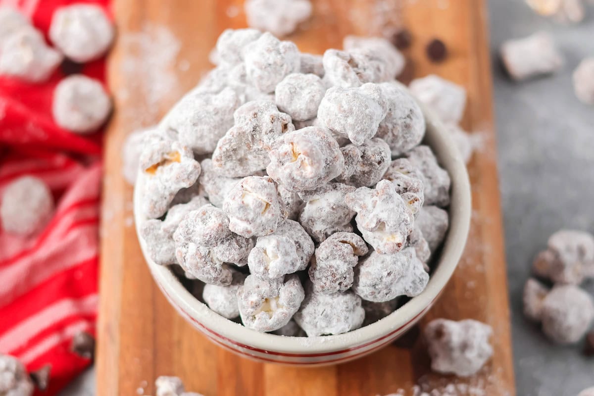 Puppy Chow Popcorn is an irresistible sweet and salty snack that's easy to make and guaranteed to be a hit. A small bowl filled with puppy chow popcorn.