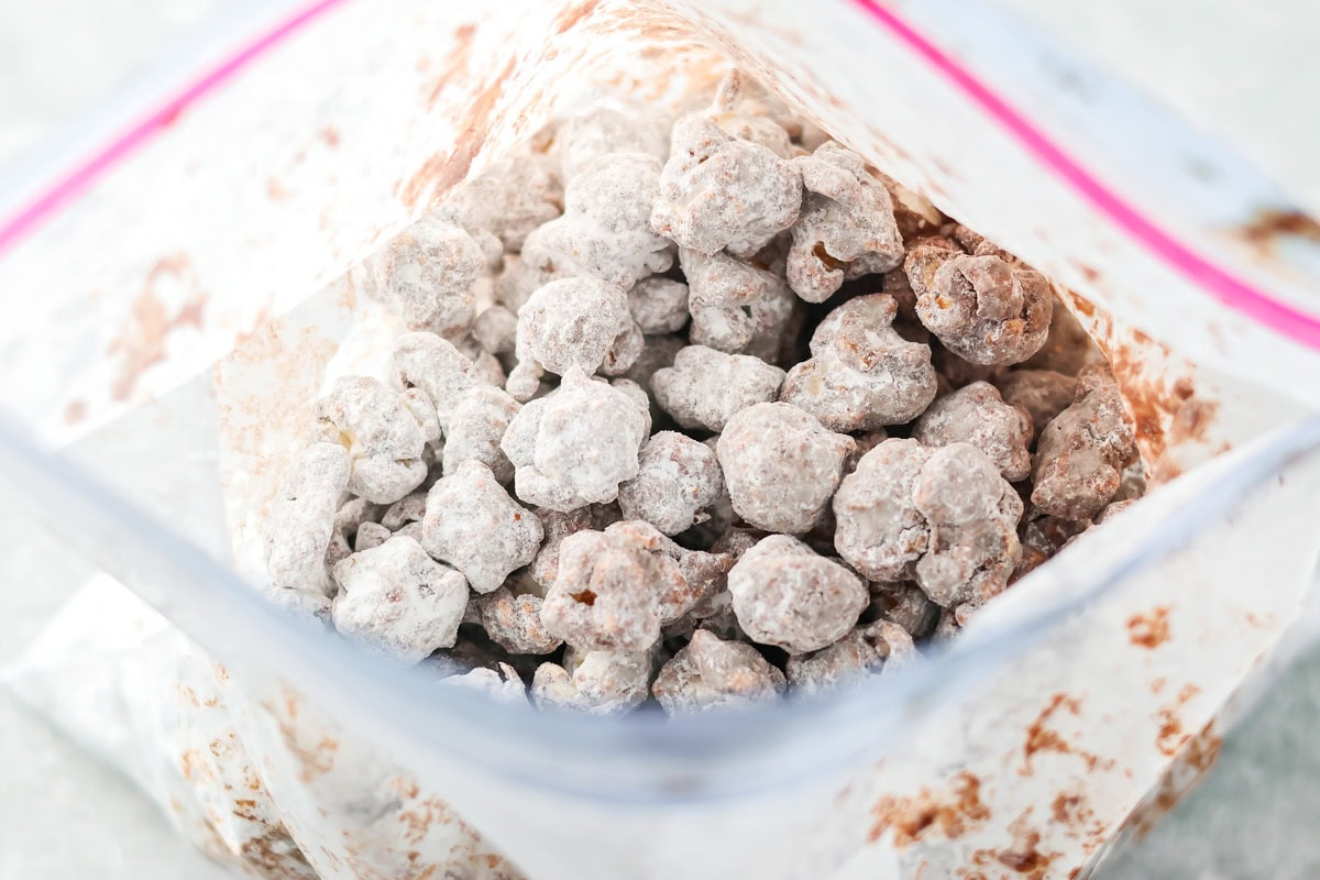 Puppy Chow Popcorn is an irresistible sweet and salty snack that's easy to make and guaranteed to be a hit. The chocolate coated Popcorn covered with powdered suagr in a Ziplock bag.