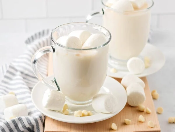 White chocolate hot cocoa in glass mug with marshmallows.