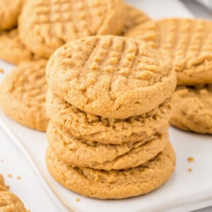 3 ingredient peanut butter cookies stacked on a cookie sheet.
