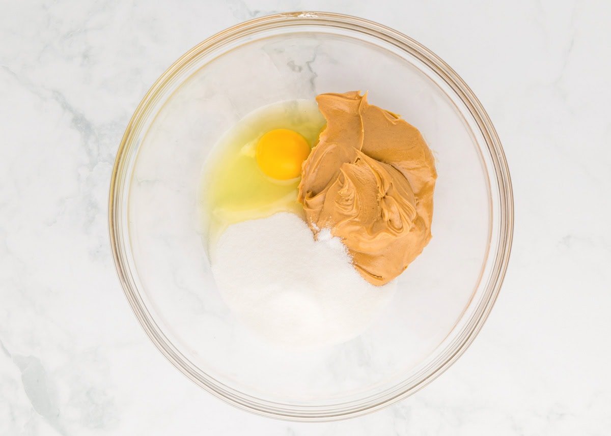 Delicious 3 ingredient peanut butter cookies take just minutes to throw together and are so easy the kids can make them! Peanut butter, sugar and egg in a mixing bowl.