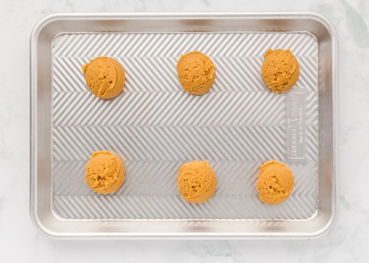 Delicious 3 ingredient peanut butter cookies take just minutes to throw together and are so easy the kids can make them! Peanut butter cookie dough balls on a baking sheet.