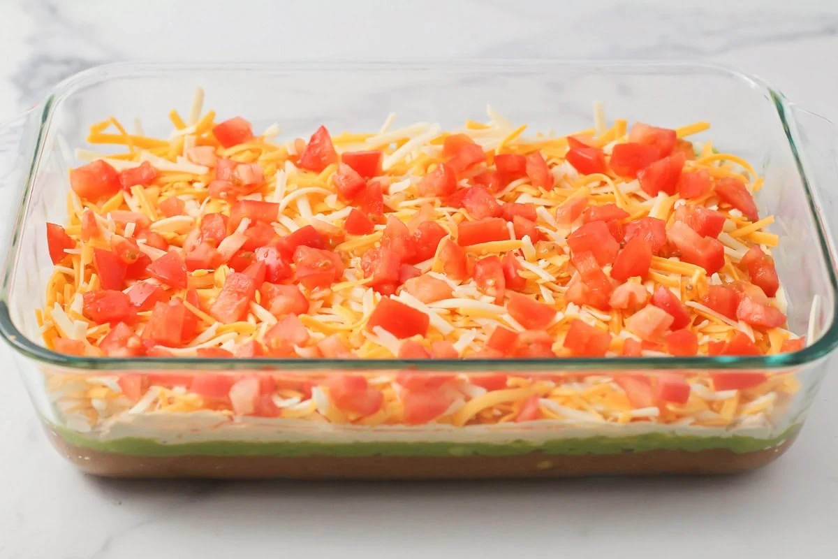 This 10-minute 7 layer bean dip is a must-have at every function! It has loads of flavor and all your favorite dip ingredients! Adding a layer of diced tomatoes to a 7 layer dip.