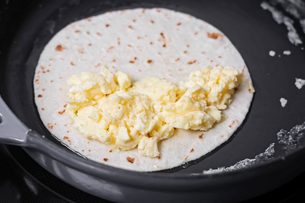 Crispy breakfast quesadillas packed with savory ingredients for a fast family meal that works for breakfast or dinner. Tortilla in a skillet with scrambled eggs over half.