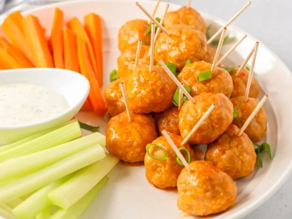 Buffalo chicken meatballs served alongside carrot sticks, ranch, and celery sticks.