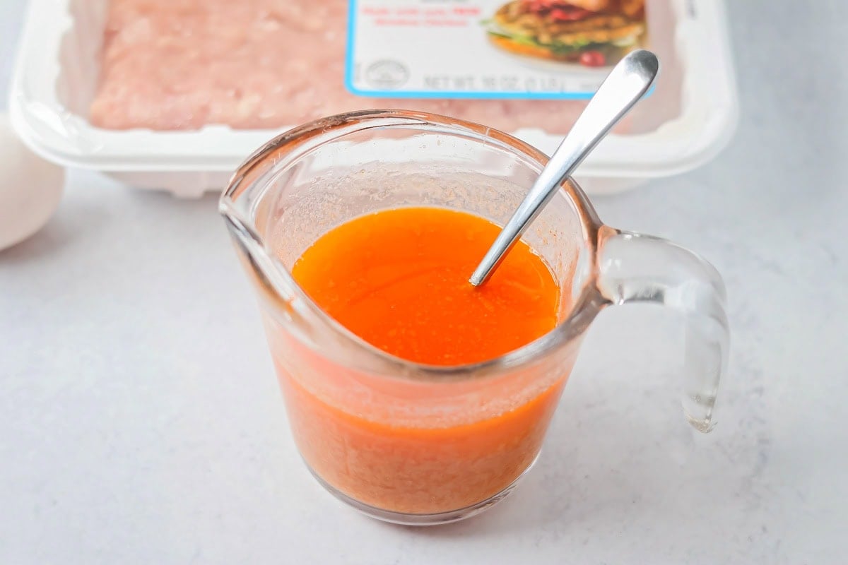 Measuring cup with buffalo sauce.
