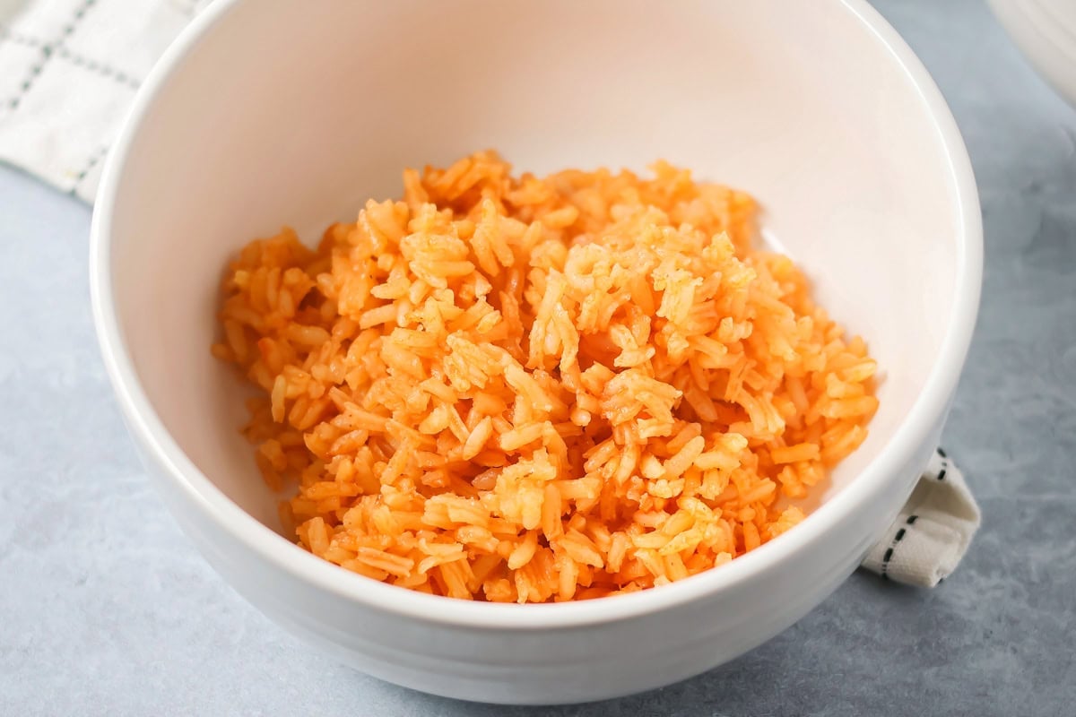 Grandma's famous caldo de pollo is a cozy chicken soup filled with chicken, rice, and Mexican spices and flavors! Bowl of cooked Spanish rice.