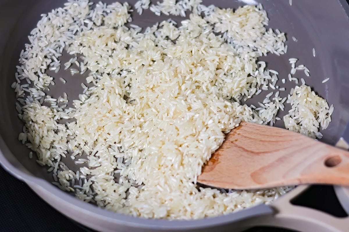 Grandma's famous caldo de pollo is a cozy chicken soup filled with chicken, rice, and Mexican spices and flavors! Toasting rice in a pan.