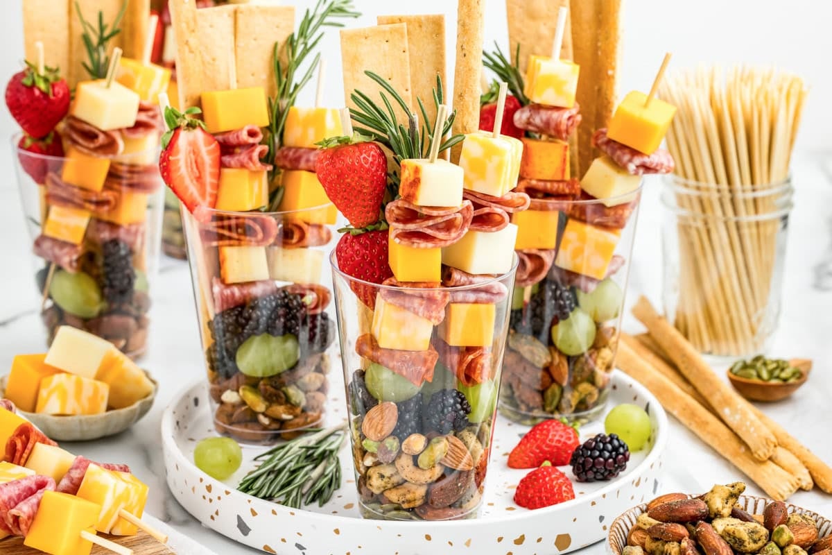 Charcuterie cups on a tray with fruit, veggies, meats and crackers inside.
