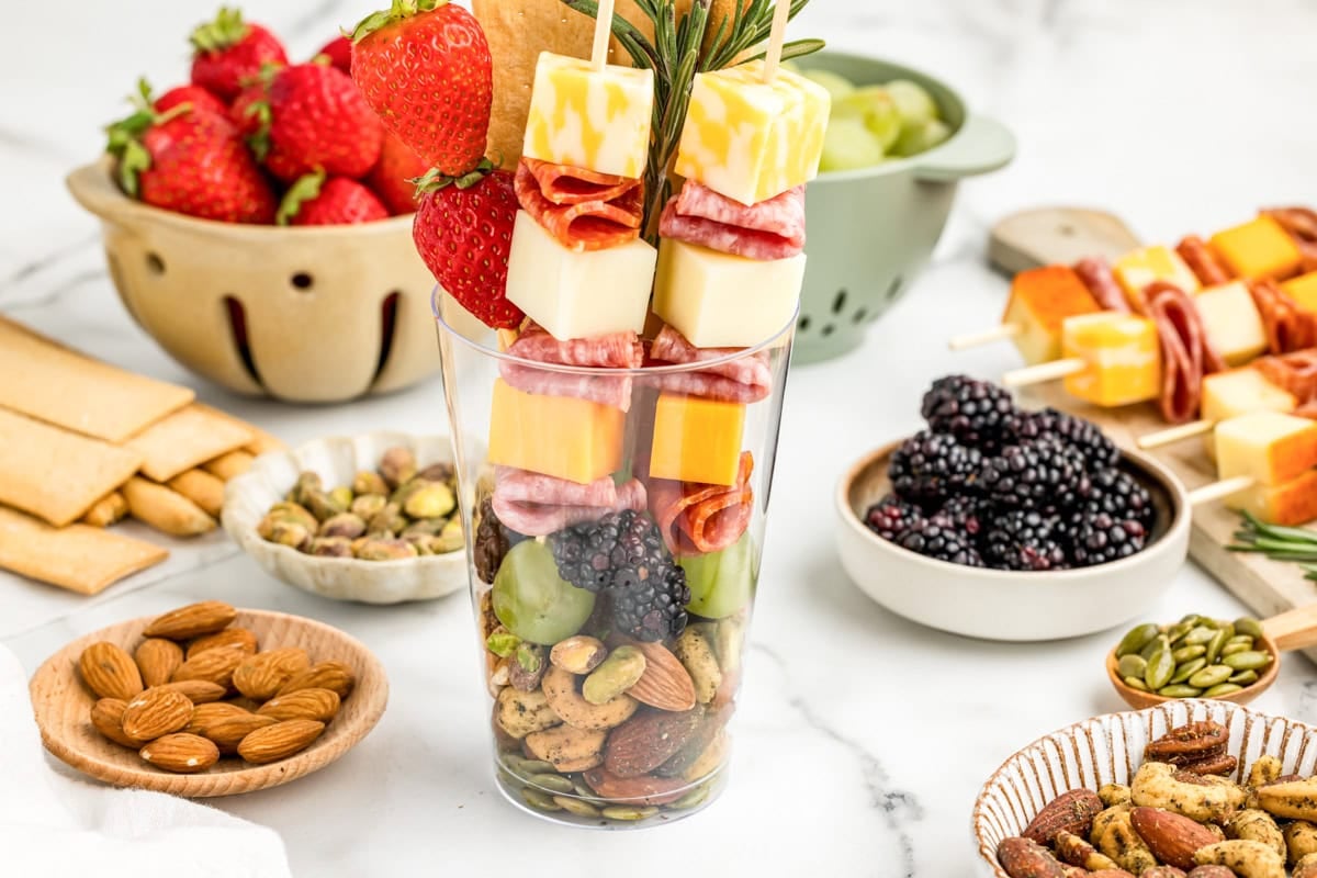 Charcuterie cups assembled with ingredients all around.