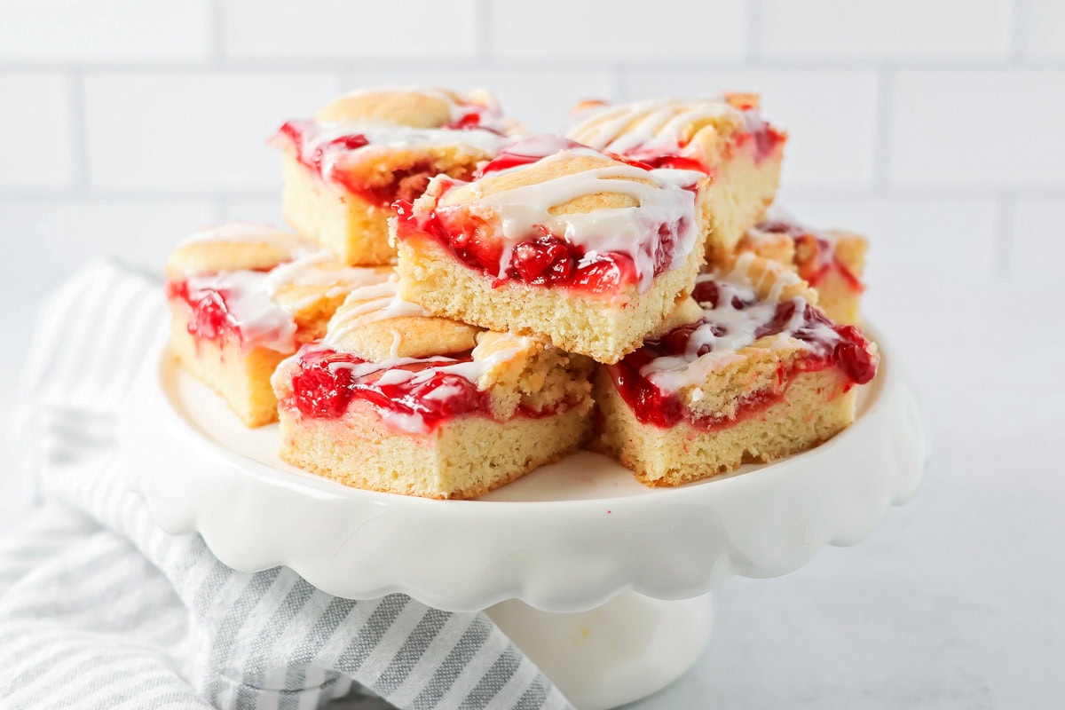 Cherry bars stacked on top of each other on a cake pan.