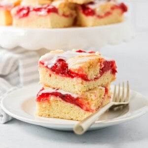 Cherry bars stacked on top of each other on white plate.