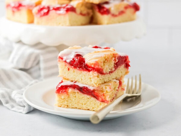 Cherry bars stacked on top of each other on white plate.