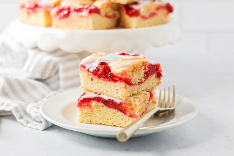 Cherry bars stacked on top of each other on white plate.