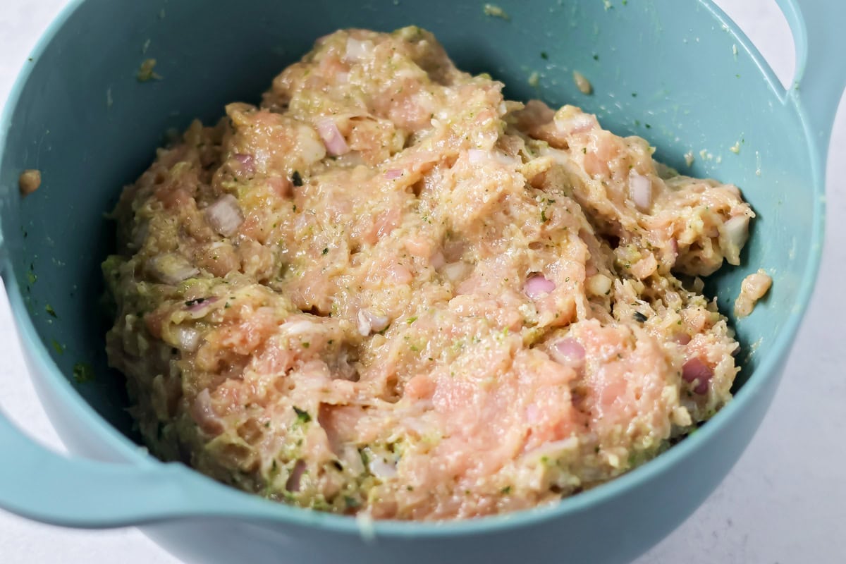 These easy chicken pesto meatballs come together in 30 minutes for a flavorful, family-friendly dinner full of basil and parmesan goodness. Mixed meatball ingredients in a bowl.